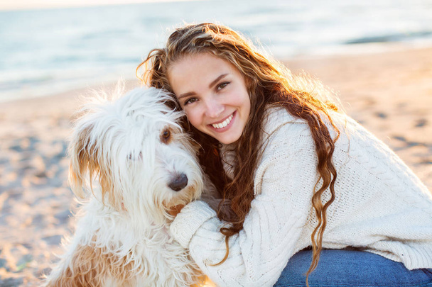 Portrait of a young beautiful woman with dog on the beach. - Foto, imagen