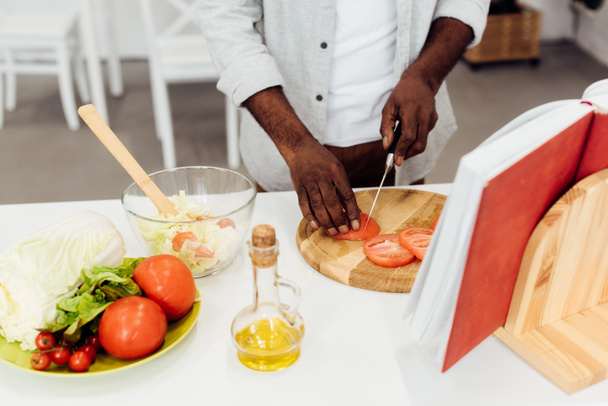 african american man slicing tomatoes on wooden chopping board  - Photo, Image