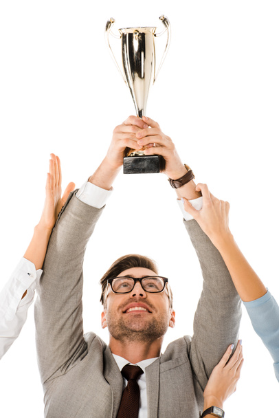 successful businessman holding trophy cup above the head while colleagues trying to get it isolated on white - Φωτογραφία, εικόνα