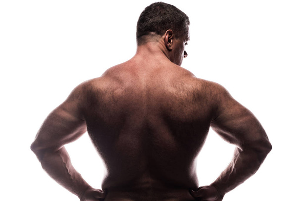 A large powerful man shows his back in the Studio without a shirt on white background, sitting on his knee - Fotoğraf, Görsel