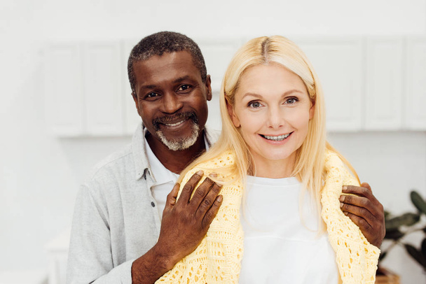happy african american man embracing smiling blonde woman  - Foto, imagen