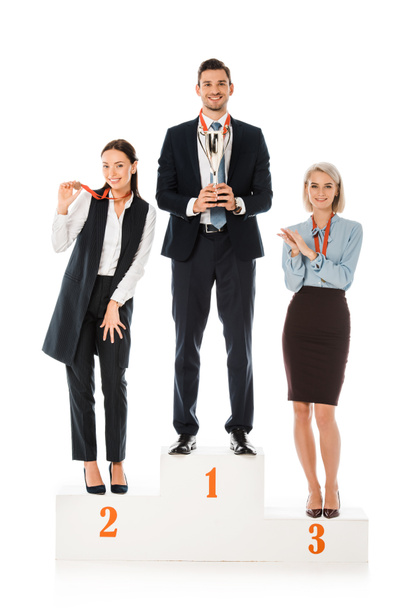 επιτυχείς επιχειρηματίες κρατώντας βραβεία ενώ στέκεται στο βάθρο νικητών που απομονώνονται σε λευκό - Φωτογραφία, εικόνα