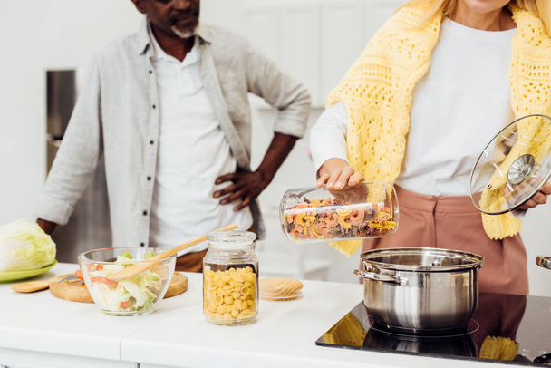 cropped view of woman standing near african american man and cooking pasta - Photo, Image