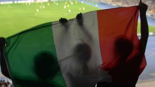 Foci rajongók a lelátókon éljenző, kedvenc csapat jumping olasz zászló - Felvétel, videó