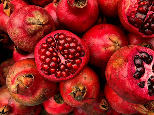 Sliced juicy bright red pomegranates. Fragment from a fruit and vegetable shop. - Photo, image