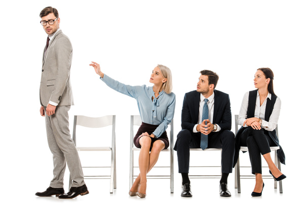 fired businessman going away from coworkers sitting on chairs isolated on white - Foto, Bild