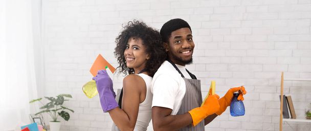 Счастливая черная пара держит моющие средства во время уборки дома
 - Фото, изображение