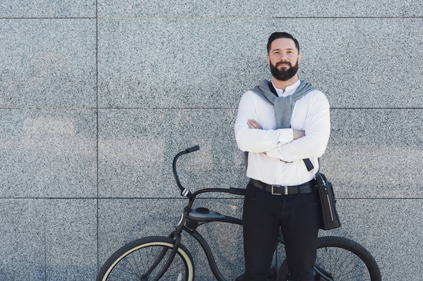 Moderne milieuvriendelijke zakenman poseren in de buurt van fiets - Foto, afbeelding