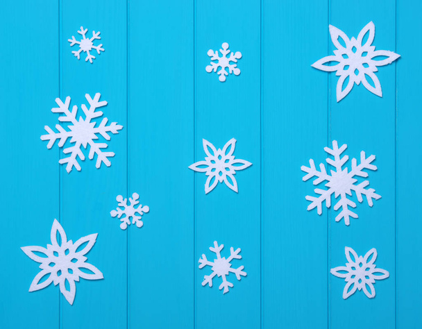Copos de nieve y estrellas sobre un fondo de madera azul - Foto, imagen