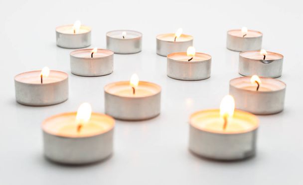 Burning paraffin candles, tealight, lies on a white background. - Photo, image