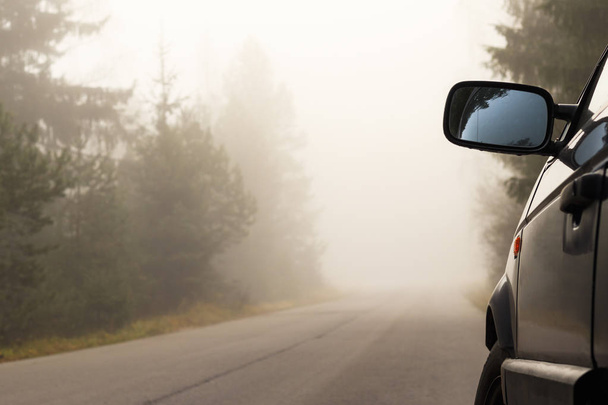 la voiture se tient sur les lignes de côté. route, il y a un brouillard naturel. la route est engloutie
. - Photo, image
