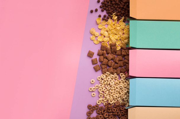 Scatole colorate con cereali sparsi su sfondo rosa
 - Foto, immagini