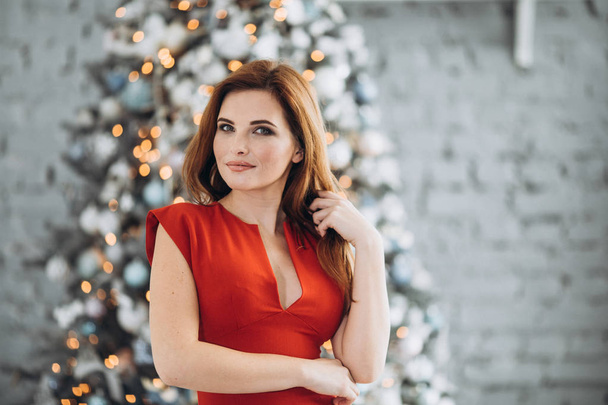 Christmas. Beautiful smiling woman Elegant over christmas tree in red dress lights background. happy new year. - Photo, Image