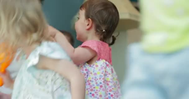 Twee vrienden met elkaar praten terwijl hun pasgeborenen te voeden en te spelen met hun peuters. - Video