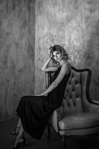 Portrait of sensual blonde woman in a long silk evening dress, fashion beauty photo in a simple interior - Valokuva, kuva