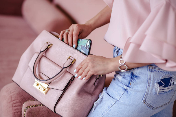Beautiful young blonde woman with light pink handbag and mobile phone. Portrait of pretty blonde girl in pink clothes. - Foto, Bild