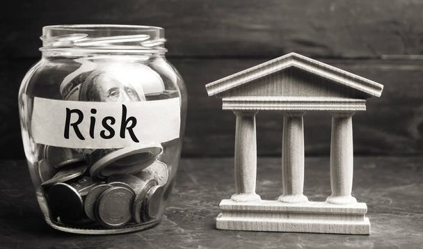 A glass jar and the inscription "risk" stands next to a state building. The concept of financial and economic risk. Unreliable investment. Unpaid loan. Financial risk management. Commercial loan - Foto, imagen
