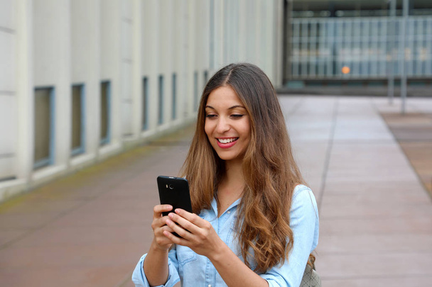Молодая счастливая деловая женщина со смартфоном ходит по пустой улице
 - Фото, изображение