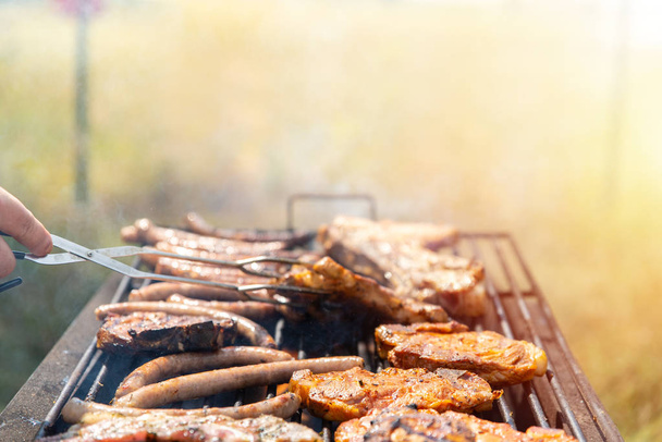 Мясо на гриле, жареные стейки, мясные ребрышки и сосиски. Выходные с семьей и друзьями на природе
 - Фото, изображение