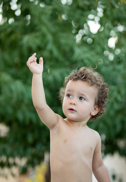 Bellissimo bambino con i capelli ricci in giardino senza t-shirt
 - Foto, immagini