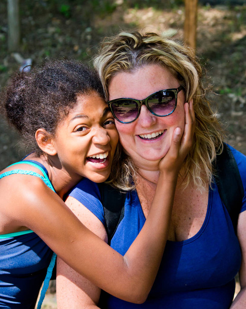 young black girl and white woman smile happily and carefree in the sun on vacation - Foto, imagen