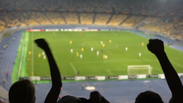 Silhouettes of fans hands in stadium while watching football match, cheering - Footage, Video