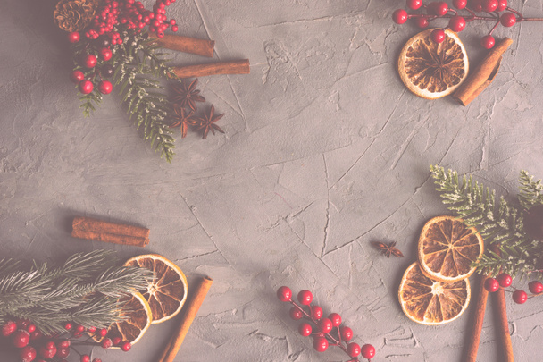 Christmas frame with fir tree, red berries, cones and decor on rustic concrete background with copy space - 写真・画像