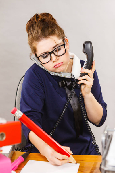 Ospalý obchodních žena dělá její práce sedí na stole mluví o telefon se nudil nebo unavený zůstat až pozdě. - Fotografie, Obrázek