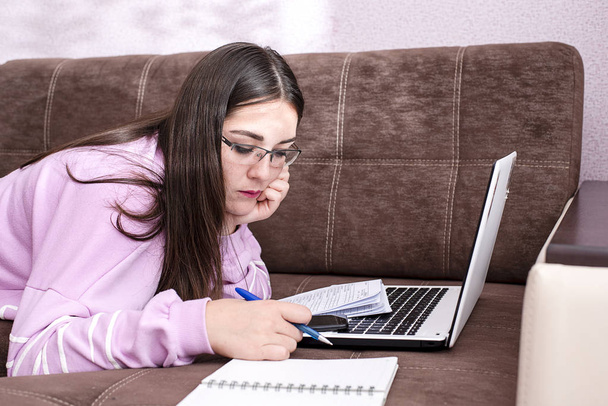 Chica estudiante acostada en el sofá y mirando el portátil
 - Foto, Imagen