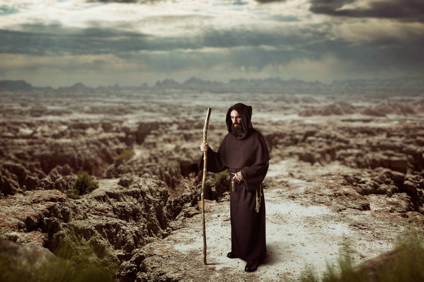 Средневековый монах в черном халате с капюшоном ходит по пустыне
 - Фото, изображение