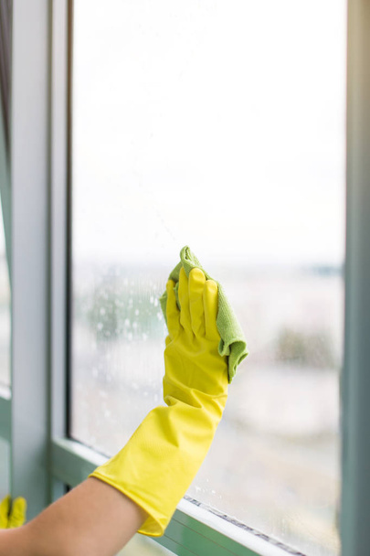 Sorrindo jovem trabalhador limpeza sabão suds na janela de vidro com rodo e pano
 - Foto, Imagem