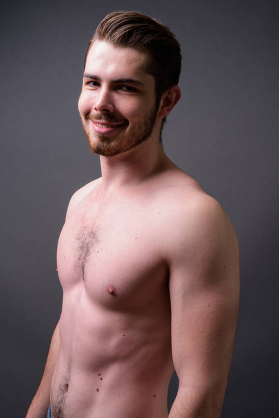 Young handsome bearded man shirtless against gray background - Foto, afbeelding