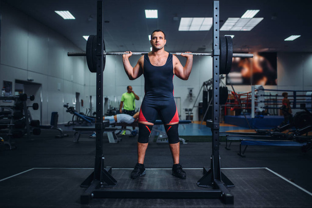 Gespierde atleet zich voorbereidt op het maken van squats met barbell in sportschool. Training van Gewichtheffen, powerlifting opleiding - Foto, afbeelding