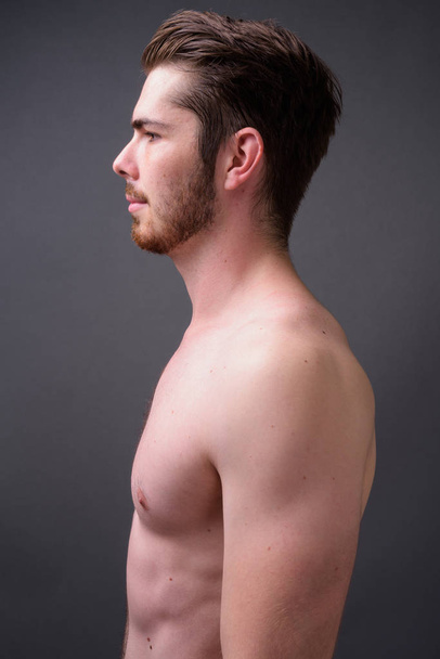 Young handsome bearded man shirtless against gray background - Photo, Image