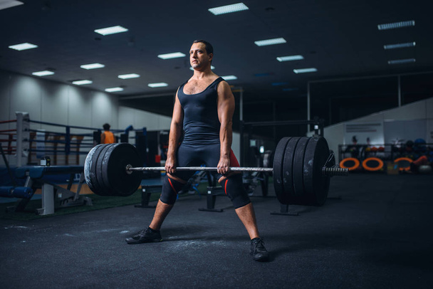 Αρσενικό powerlifter προετοιμασία deadlift ένα barbell στο γυμναστήριο. Προπόνηση βαρών, άρση κατάρτισης, αθλητής λειτουργεί με βάρος σε αθλητική λέσχη - Φωτογραφία, εικόνα