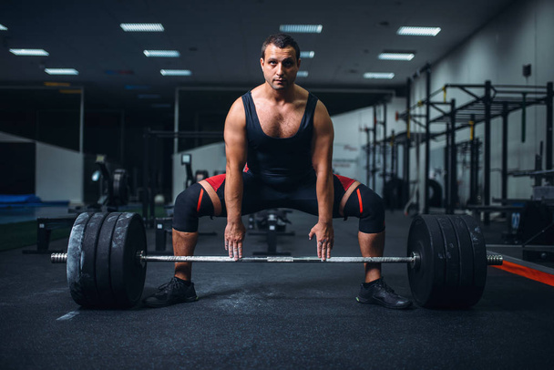 Αρσενικό powerlifter προετοιμασία deadlift ένα barbell στο γυμναστήριο. Προπόνηση βαρών, άρση κατάρτισης, αθλητής λειτουργεί με βάρος σε αθλητική λέσχη - Φωτογραφία, εικόνα