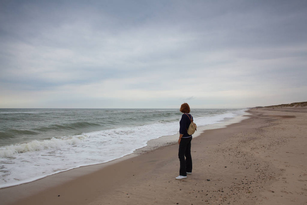 Hvide Sande, Denmark - August 13,2018: Lonely woman on the beach. Hvide Sande in Denmark has 40 km sandy beaches.Hvide Sande is the epitome of beaches, dunes, sun, wind and especially clean air.West Jutland, Denmark. - Foto, Bild