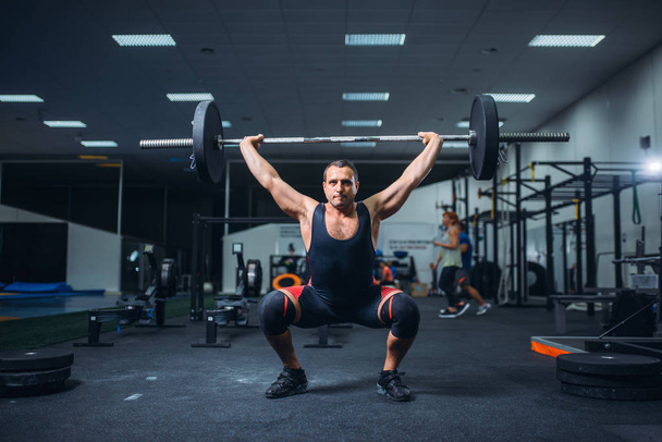 Ισχυρό αρσενικό powerlifter κάνει deadlift ένα barbell στο γυμναστήριο. Προπόνηση βαρών, άρση κατάρτισης, αθλητής λειτουργεί με βάρος σε αθλητική λέσχη - Φωτογραφία, εικόνα