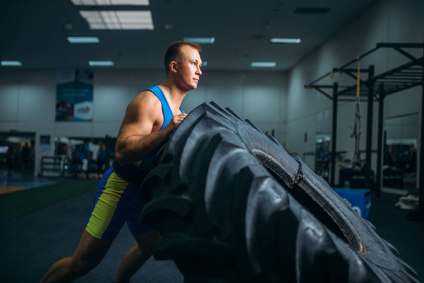 Silné mužské sportovce dělat sílu cvičení s nákladní pneumatiky v posilovně, cvičení crossfit. Cross fit trénink ve fitness klubu - Fotografie, Obrázek