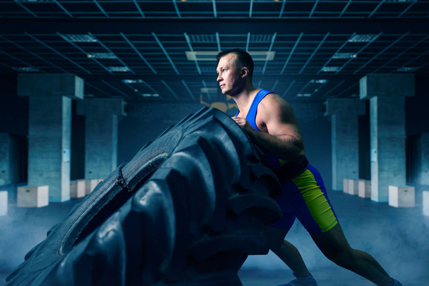 Athlète masculin fort faisant de l'exercice de force avec pneu de camion dans la salle de gym, entraînement Crossfit. Entraînement cross fit en club sportif
 - Photo, image