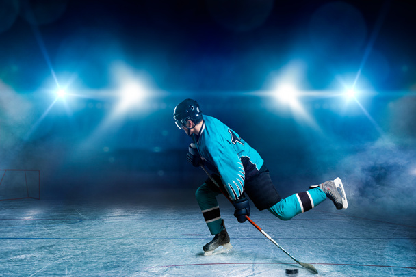 Un giocatore di hockey che pattina sull'arena di ghiaccio, riflettori su sfondo nero. Persona di sesso maschile in casco, guanti e uniformi tiene bastone in mano
 - Foto, immagini