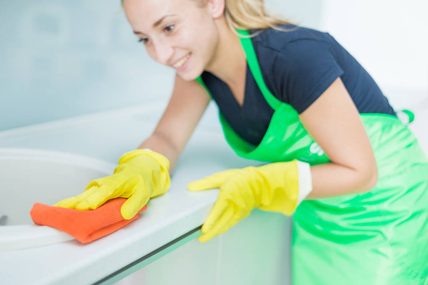 Closeup of female hands in rubber yellow gloves cleaning the cooker panel at home kitchen. Home, housekeeping concept. cleaning service - Foto, immagini