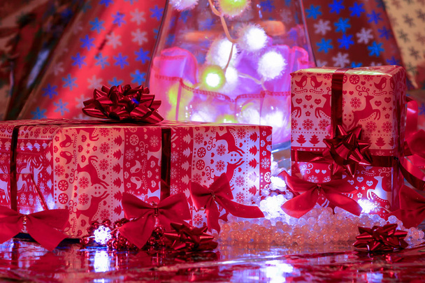 Χριστουγεννιάτικα δώρα που θέτουν μπροστά από πολύχρωμους φωτισμούς - Φωτογραφία, εικόνα