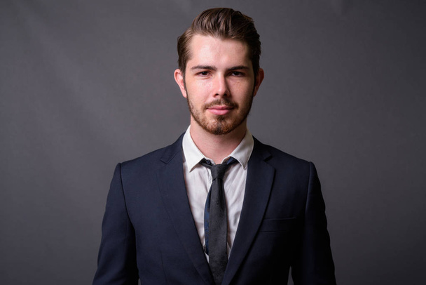 Fiatal jóképű szakállas üzletember szürke háttér - Fotó, kép