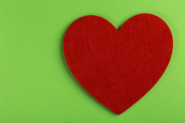 Red felt heart on bright green background. St. Valentine's day. Copy space - Foto, afbeelding