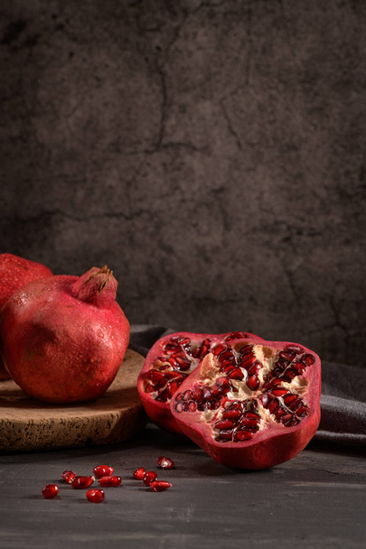 Ripe pomegranate fruit and pomegranate seeds on dark background, close-up. Healthy vegetarian antioxidant organic diet food - Foto, immagini