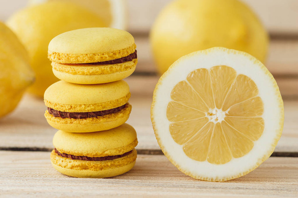 Yellow french macarons with lemons on the wooden board, soft focus background - Foto, immagini