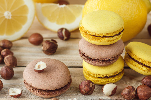 Yellow and brown french macarons with lemon and hazelnuts, soft focus background - Photo, Image
