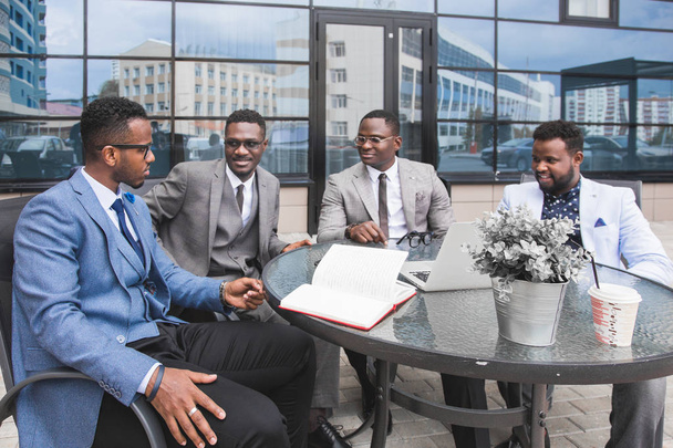 Group of happy diverse male and female business people team in formal gathered around laptop computer in bright office against the background of a glass building - Foto, Imagem