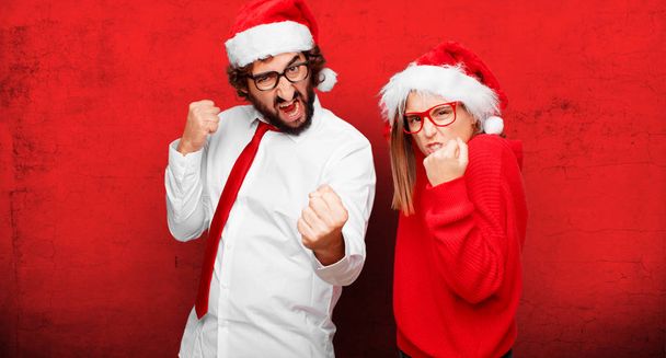 νεαρό ζευγάρι εκφράζοντας Χριστούγεννα έννοια. Ζευγάρι και το φόντο σε διαφορετικά στρώματα. - Φωτογραφία, εικόνα